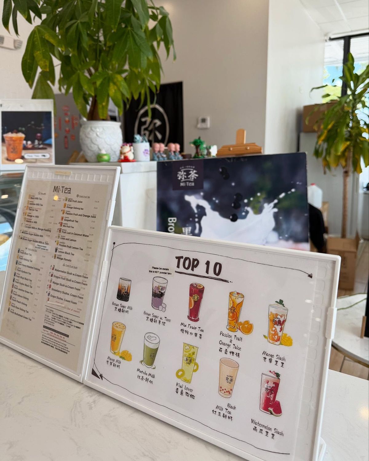 Không gian quầy order hiện đại trưng bày hai dạng menu: một bảng menu chi tiết bằng tiếng Anh kèm giá tiền đặt trong khung đứng và một bảng minh họa "Top 10" vẽ tay sinh động giúp khách hàng nhanh chóng lựa chọn món signature.